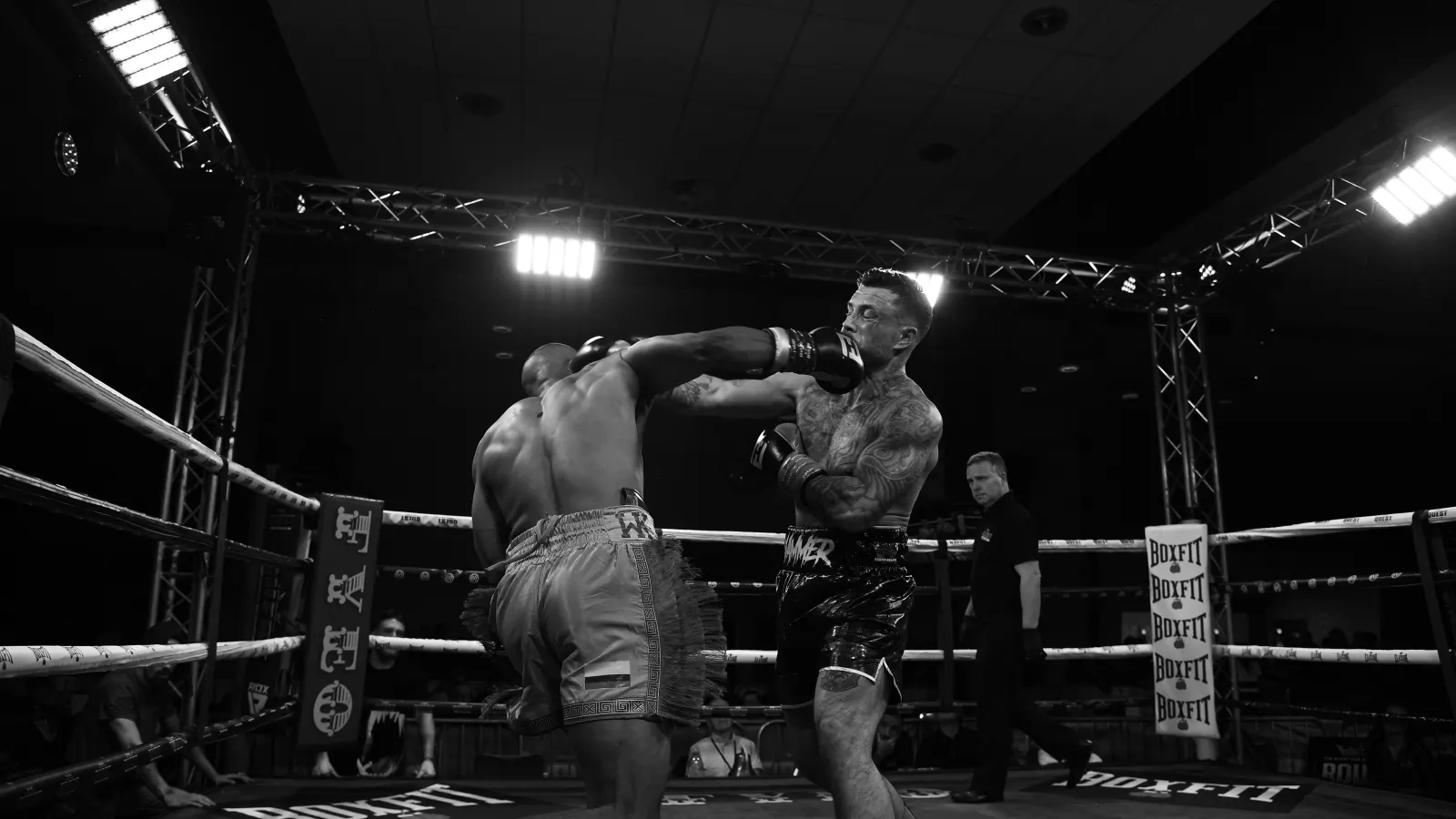 Wide view of a boxing ring under show lighting, black and white
