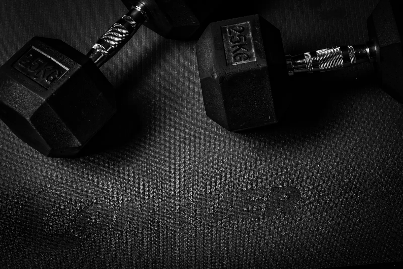 Dumbbells resting on a Conquer exercise mat, product detail