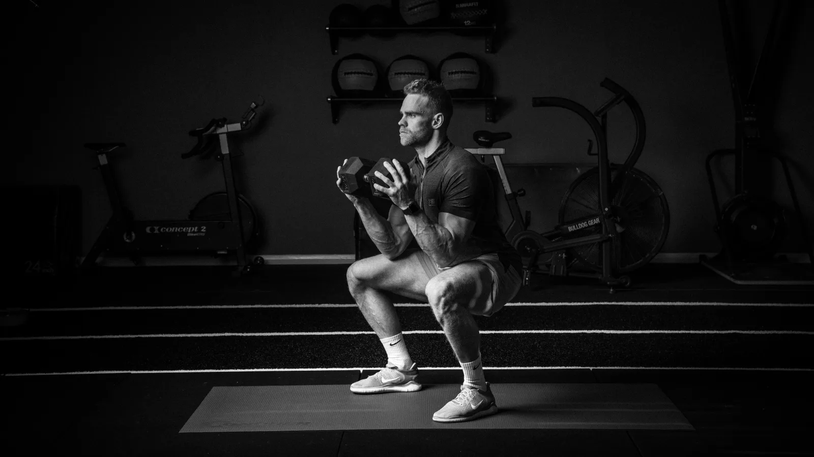 Athlete performing a weighted squat, side-lit, Conquer campaign